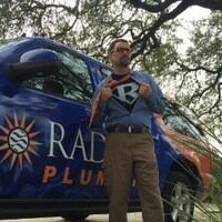 Brad Casebier pulling open his button-up shirt to show a t-shirt with a "B" underneath as he stands in front of his pick-up